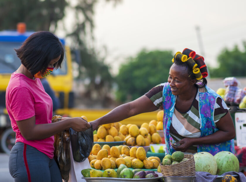 African American female in a protective face mask shopping for fruit at a market